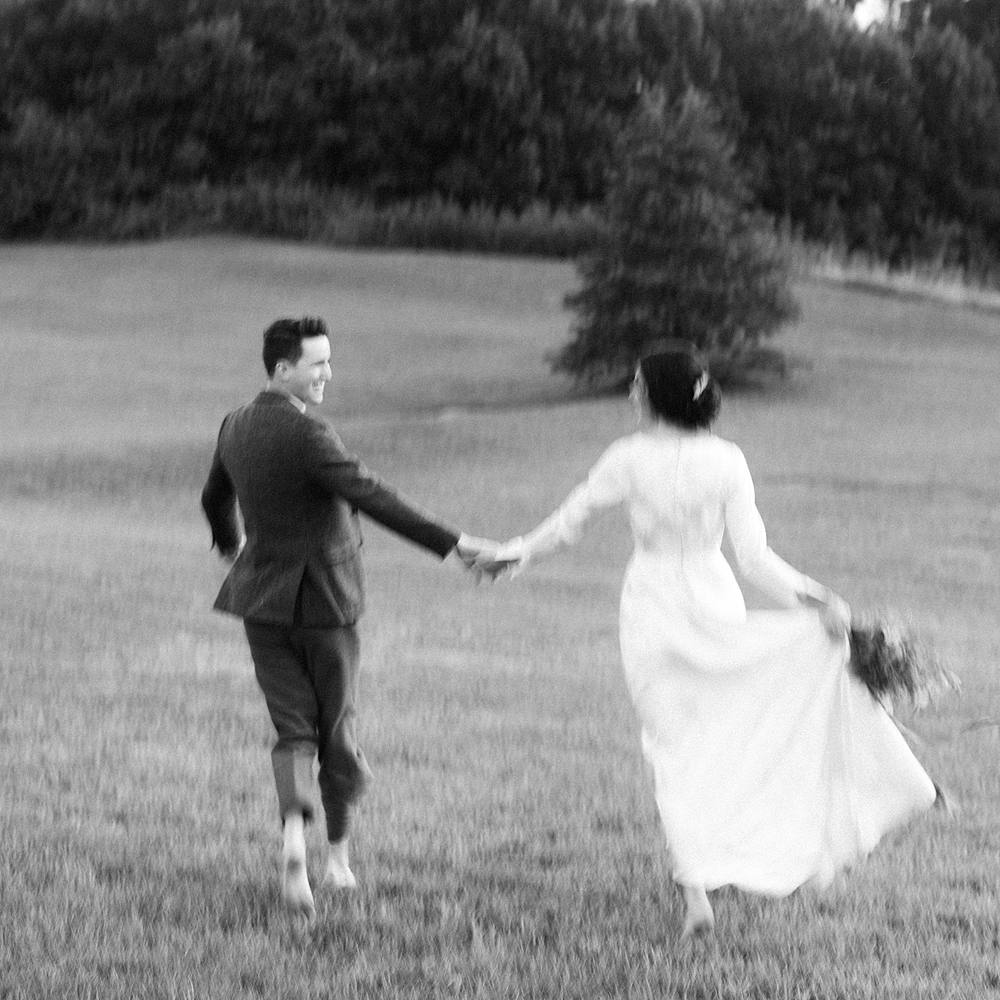 black and white film portrait of blurry wedding couple running at hotel domestique in south carolina with vintage dress