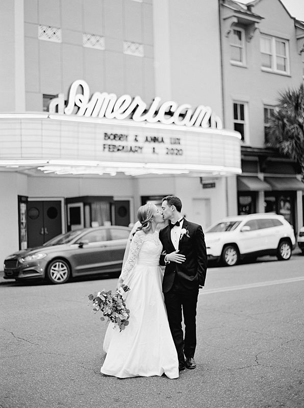 bride and groom black and white film portrait in front of charleston's american theater for william aiken house wedding