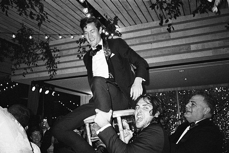 groom in chair during horah dance at a charleston sc wedding captured on kodak p3200 film with a contax t3